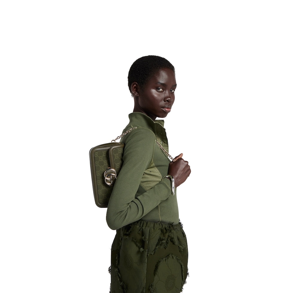 Person wearing a green outfit with a matching bag on a white background