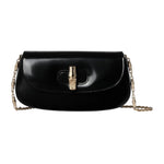 Black handbag with gold clasp and chain strap on a light gray background