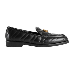Black quilted loafer with gold buckle on a light gray background