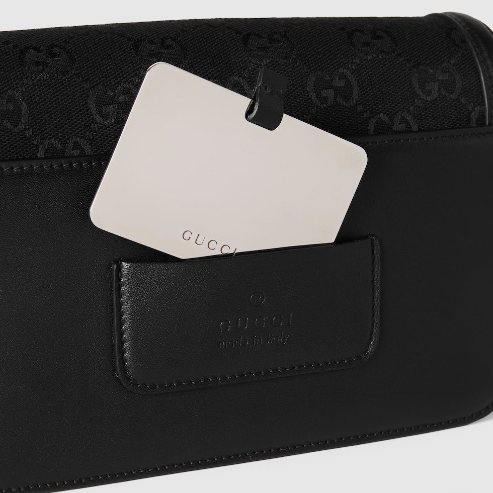 Black Gucci clutch bag with a visible brand tag on a white background