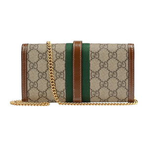 Designer handbag with patterned fabric and gold chain strap on a light gray background