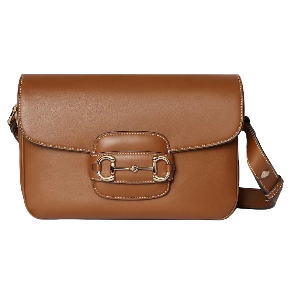 Brown leather luxury Gucci handbag with a gold buckle on a light gray background