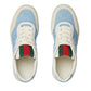 Pair of Gucci sneakers with blue pattern and red and green striped socks on a white background