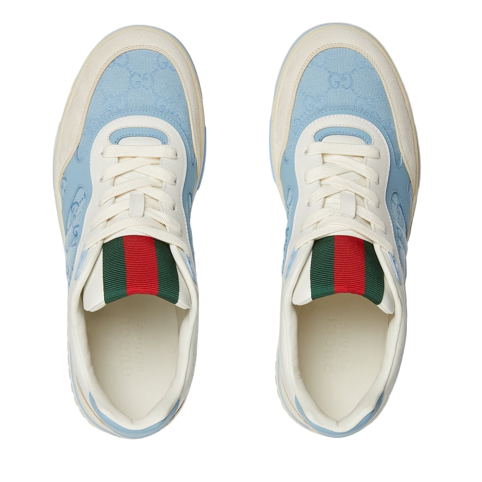 Pair of Gucci sneakers with blue pattern and red and green striped socks on a white background