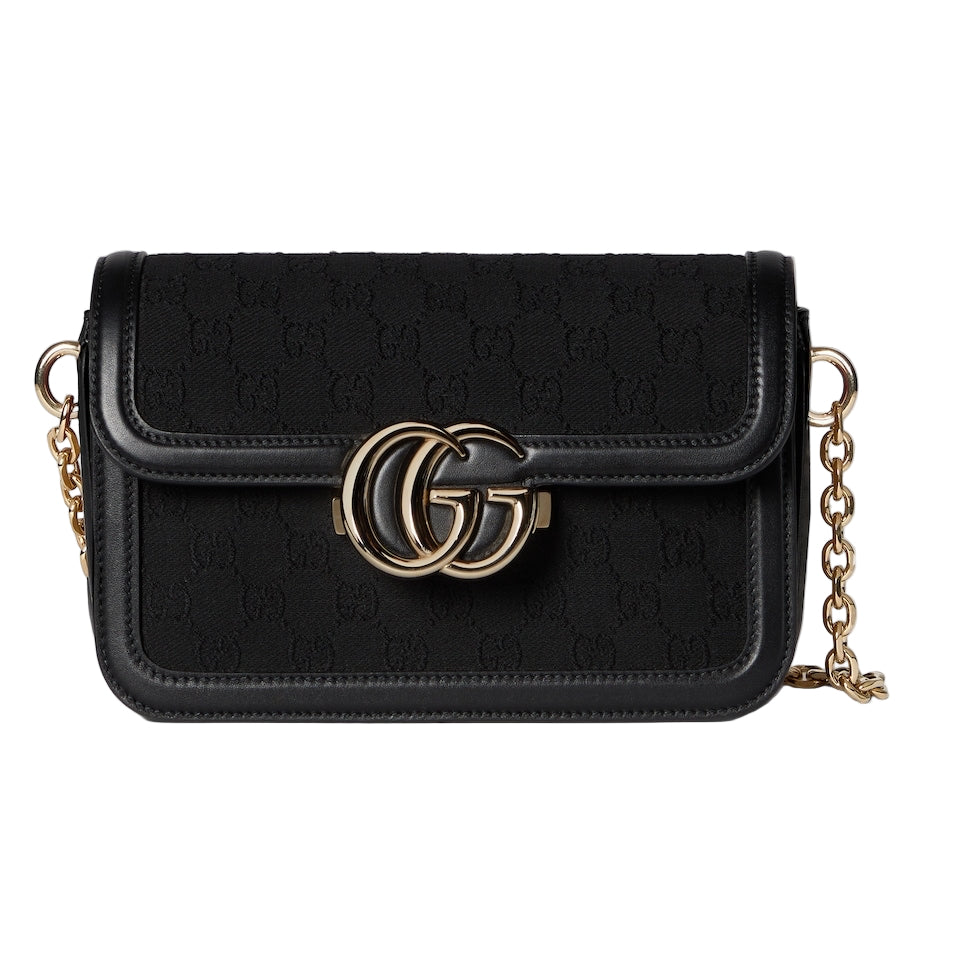 Black handbag with gold chain and logo on a light gray background