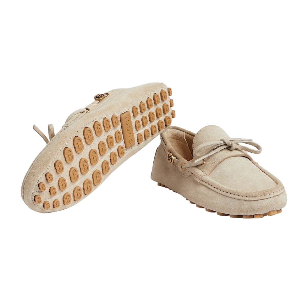 Pair of beige loafers with brown soles on a light gray background