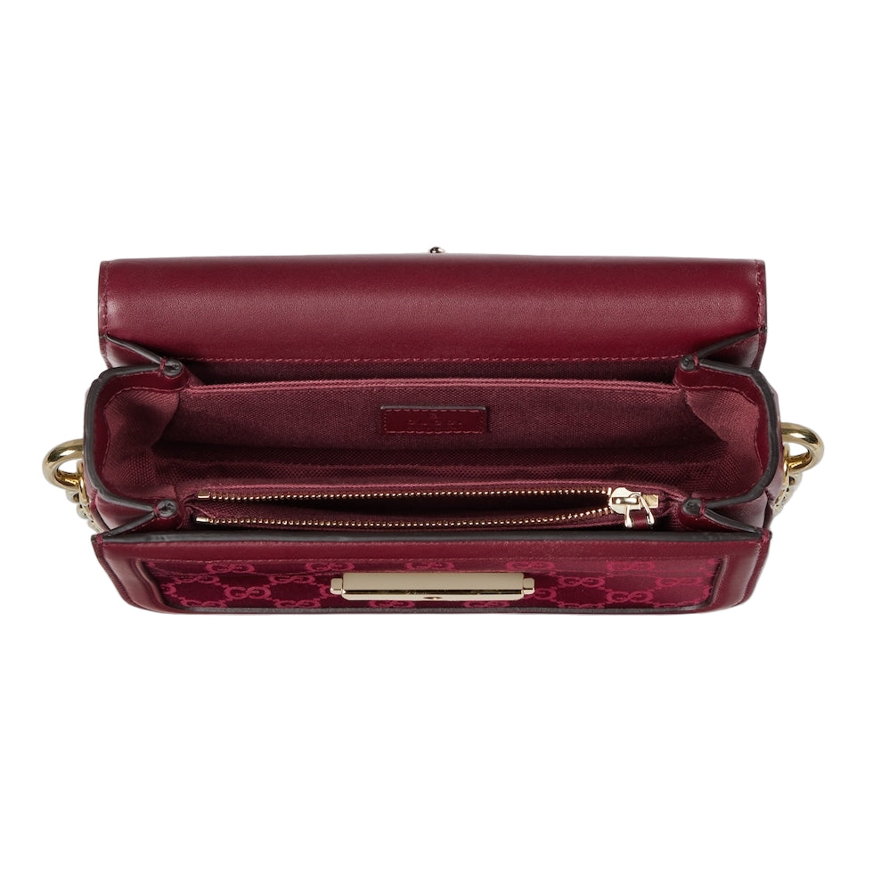 Maroon handbag with gold accents on a light gray background