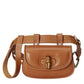 Brown leather belt bag with a buckle on a light gray background