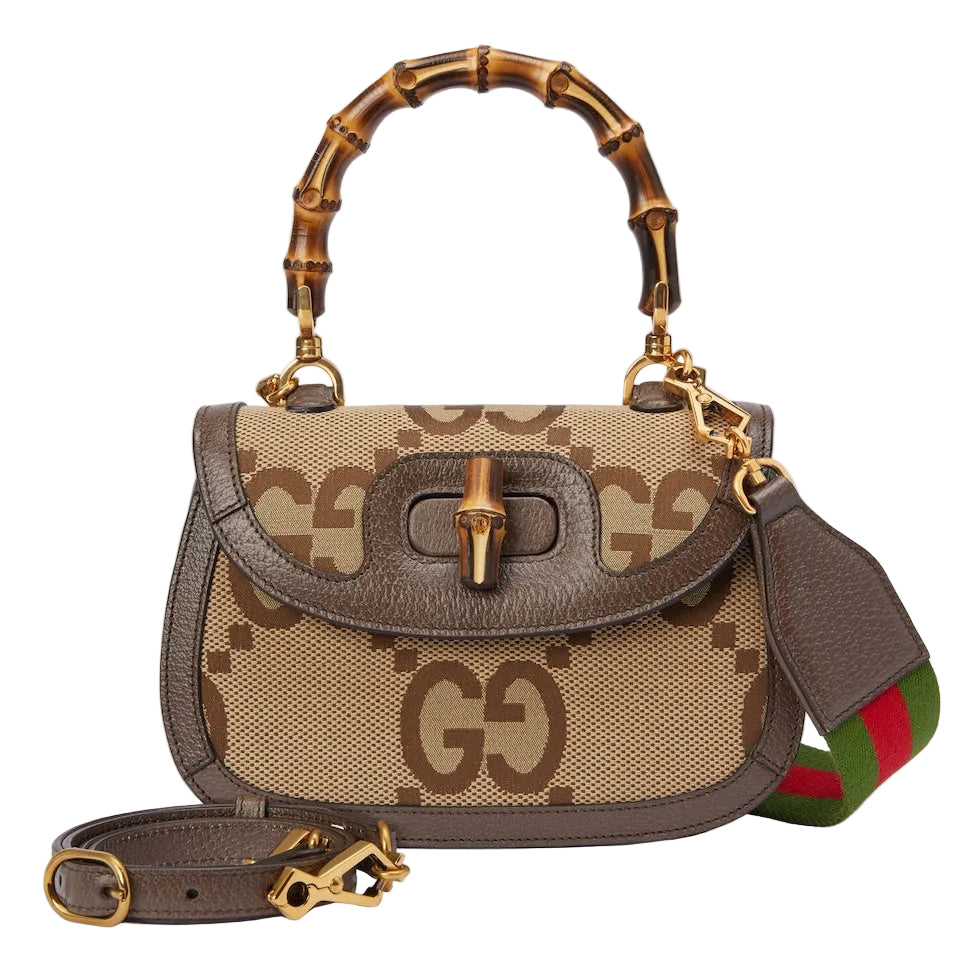 Designer handbag with bamboo handle and visible brand logo on a light gray background