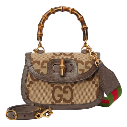 Designer handbag with bamboo handle and visible brand logo on a light gray background