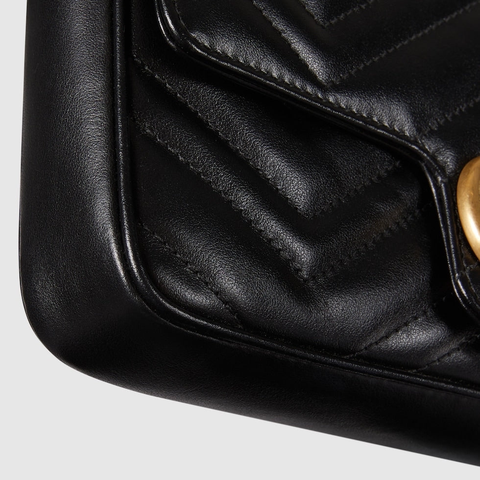 Close-up of a black quilted handbag with a gold clasp on a light gray background
