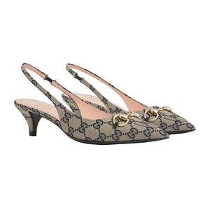 Pair of Gucci high heels with patterned design and gold accents on a light gray background