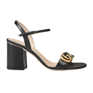 Black high-heeled sandal with gold buckle on a light gray background