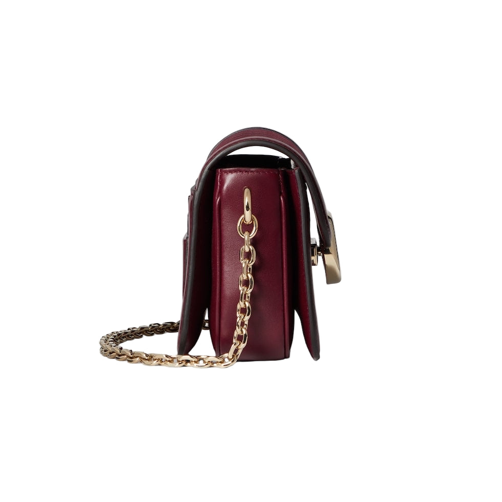 Burgundy handbag with gold chain on a light gray background