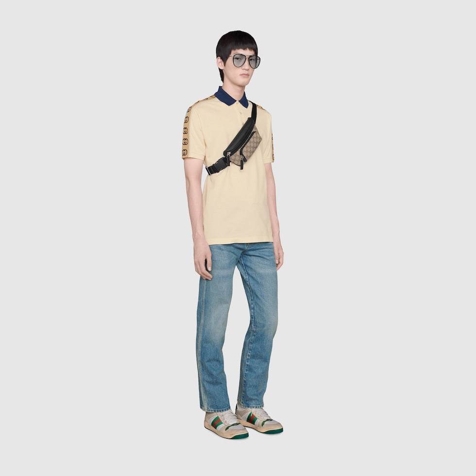 Person wearing a light yellow polo shirt with black accents and blue jeans on a white background
