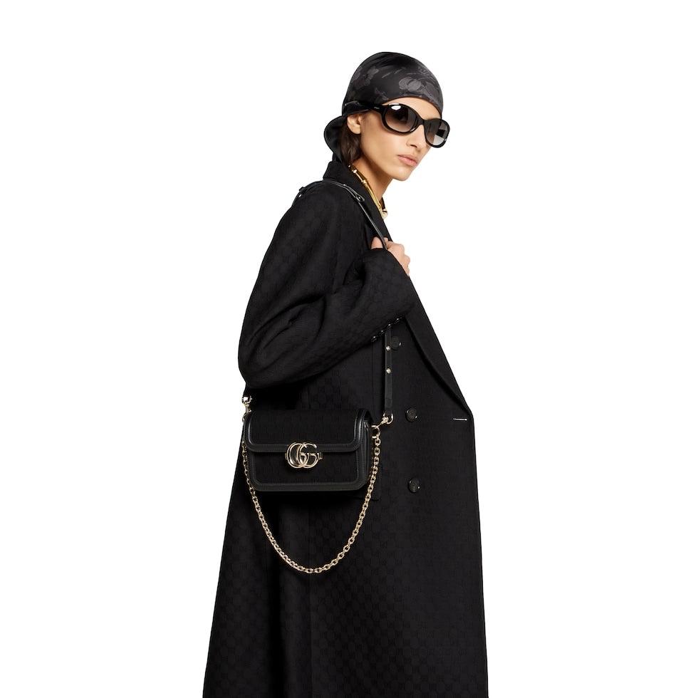 Woman holding a black handbag with a chain strap on a white background