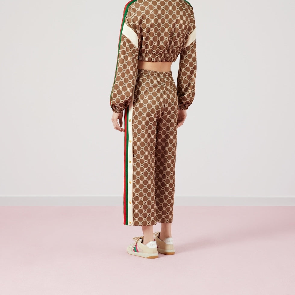 Person wearing a patterned outfit with a visible brand logo on a pink background