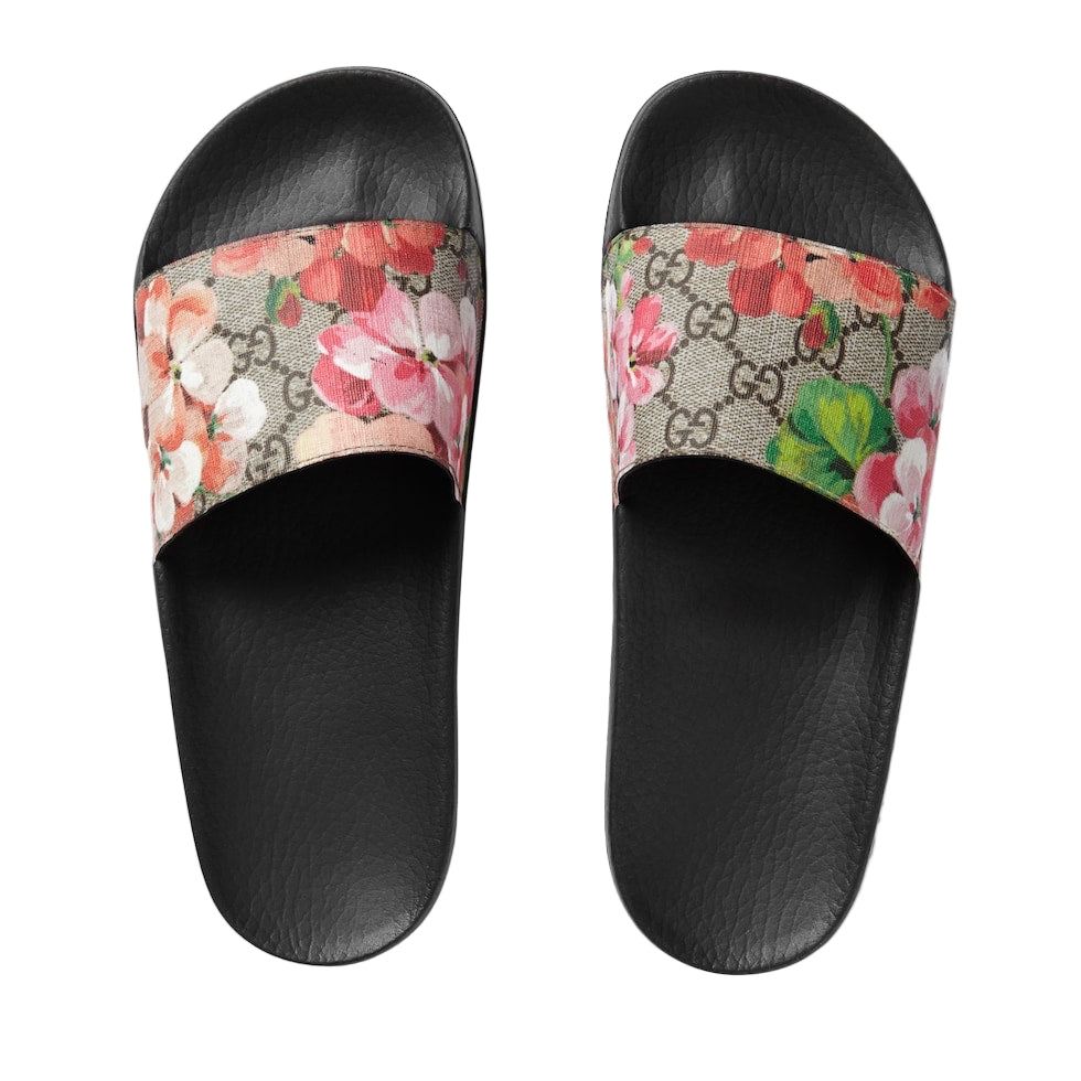 Pair of Gucci slides with floral strap on a light gray background