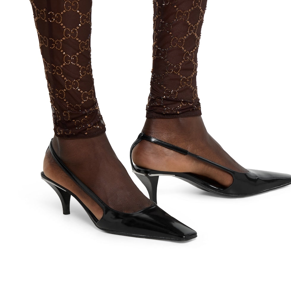 Black high-heeled shoes worn with brown patterned tights on a white background