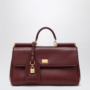 Brown leather handbag with gold accents on a light gray background