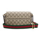 Designer handbag with patterned body and colorful strap on a light gray background