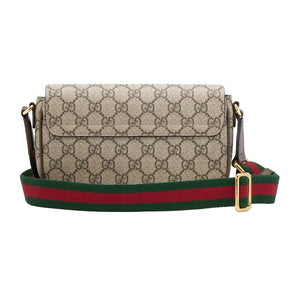 Designer handbag with patterned body and colorful strap on a light gray background