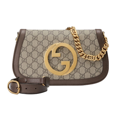 Designer handbag with gold chain and logo on a light gray background