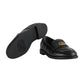 Black loafers with a gold logo on a light gray background