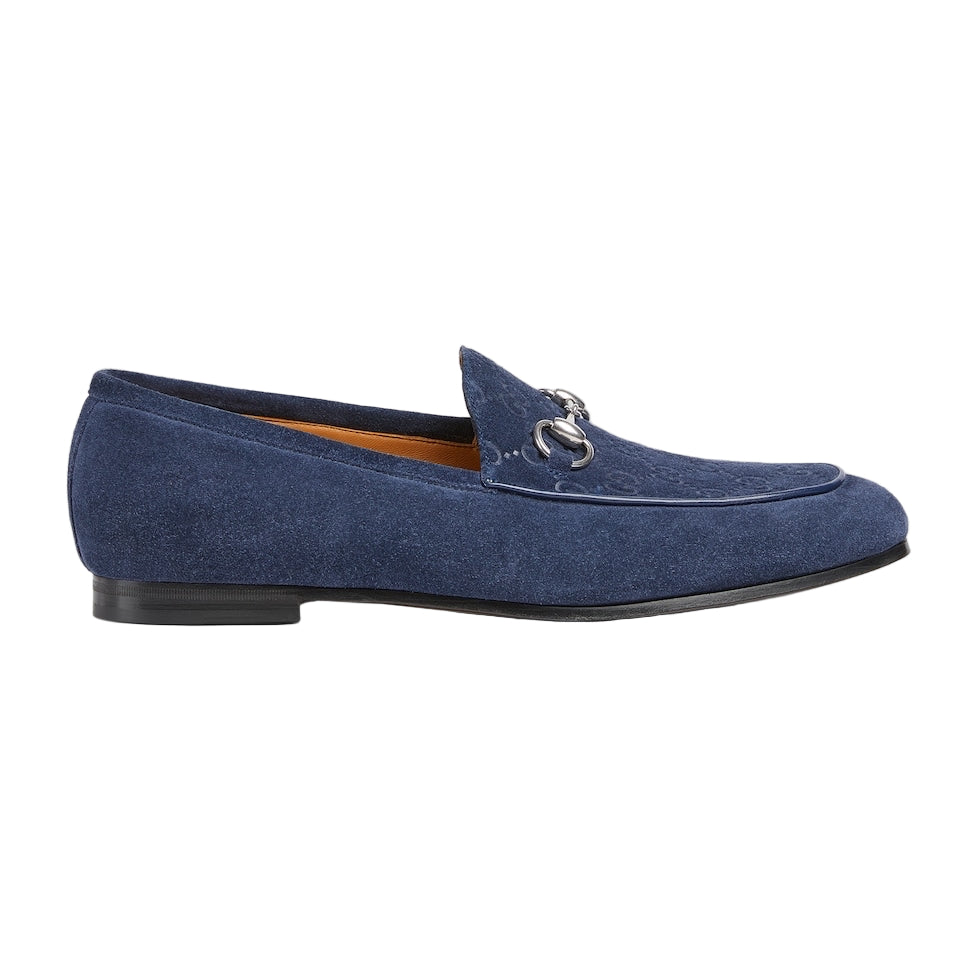 Blue suede loafer with a silver buckle on a light gray background