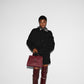 Person wearing a black outfit with a red handbag on a white background