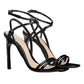 Black strappy high-heeled sandals on a light gray background