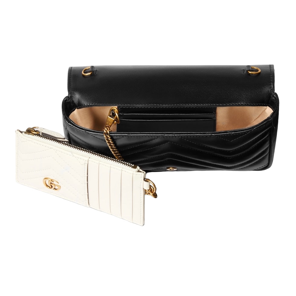 Black handbag and white wallet with gold accents on a light gray background