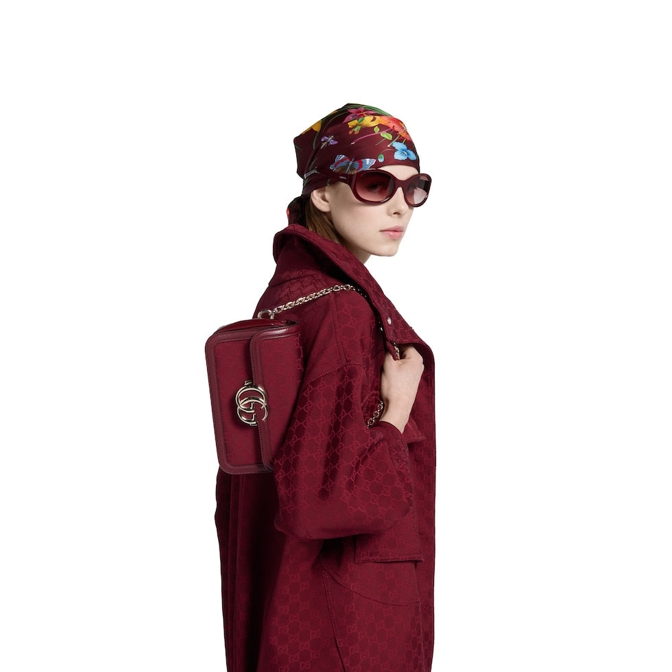 Woman in a red coat and sunglasses holding a red handbag on a white background