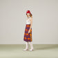 Woman wearing a patterned skirt, white top, and red hat against a plain background