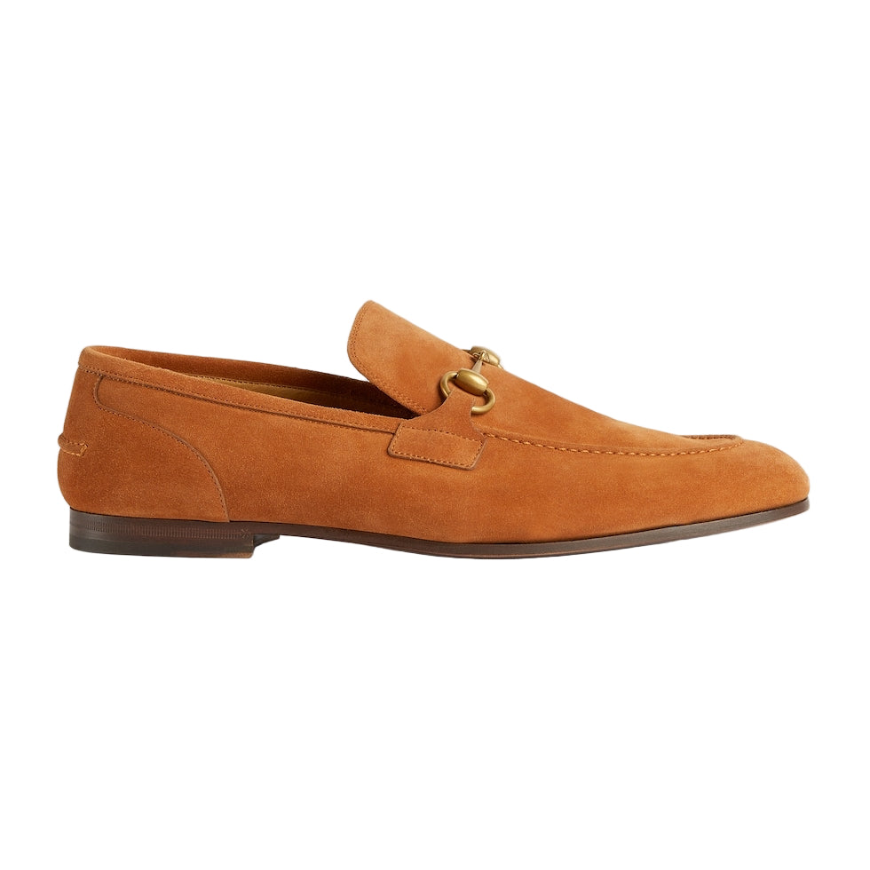 Brown suede loafer with gold buckle on a light gray background
