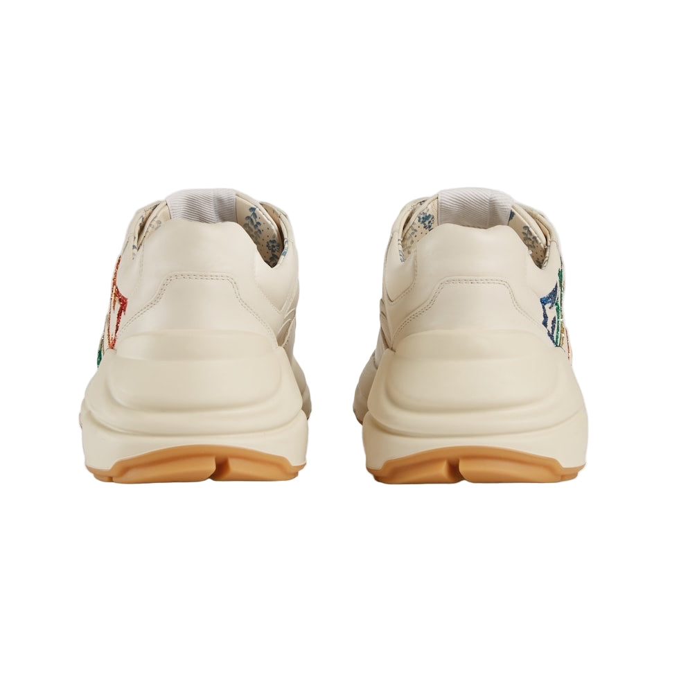 Pair of beige sneakers with floral patterns on a light gray background