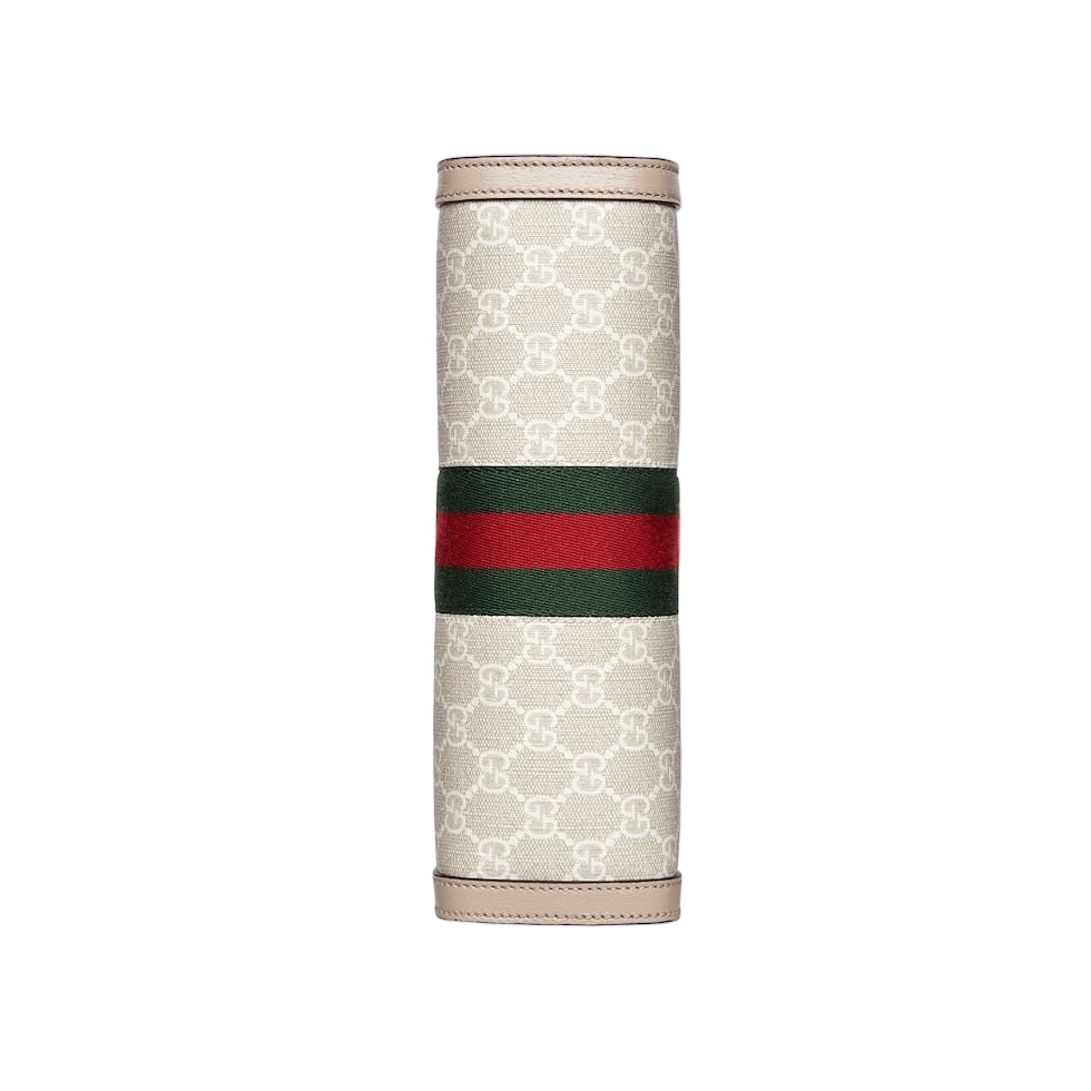 Gucci travel case with monogram pattern and red and green stripe on a light gray background