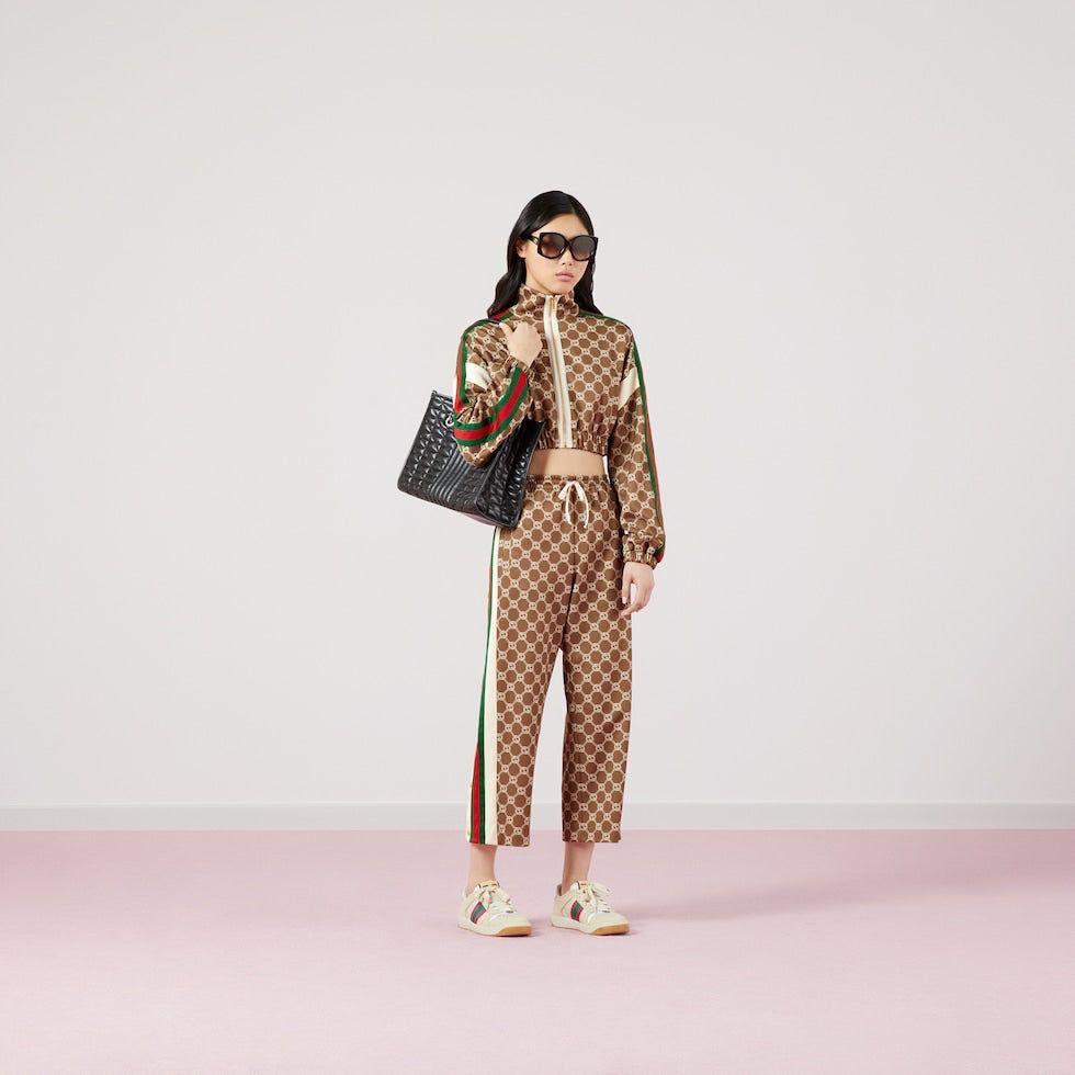 Person wearing a Gucci tracksuit with a handbag on a white background