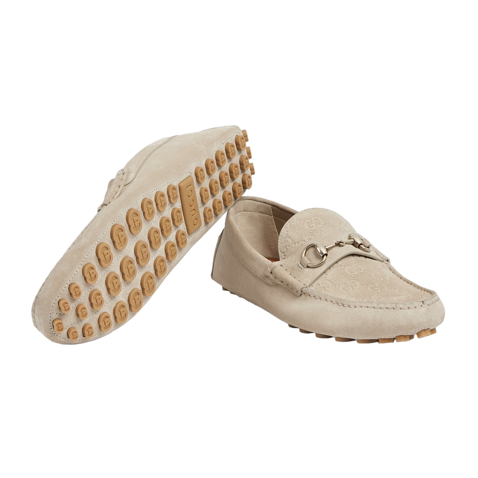 Beige loafers with gold accents on a light gray background