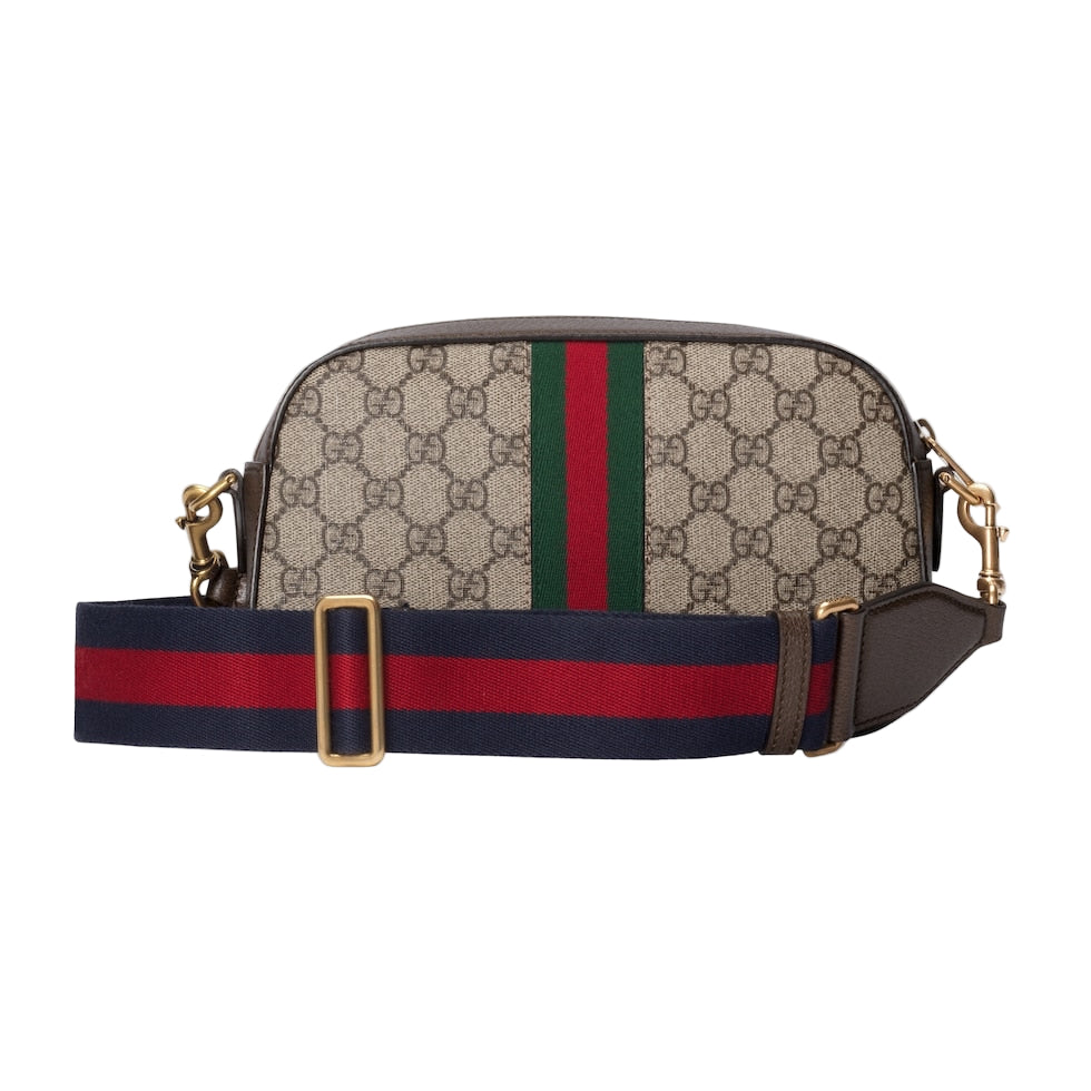 Gucci handbag with signature pattern and web strap on a light gray background
