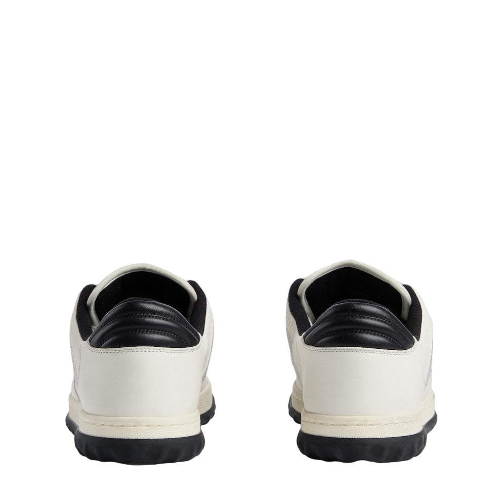White sneakers with black soles on a light gray background