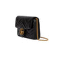 Black quilted handbag with gold chain on a light gray background