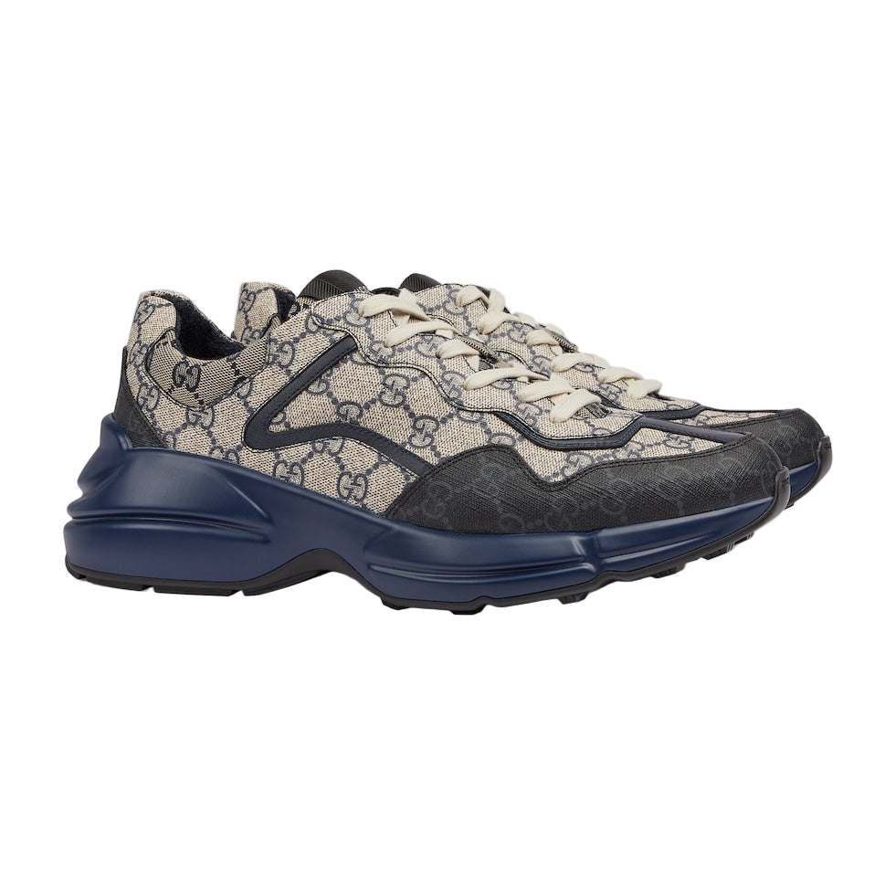 Gucci sneaker with patterned upper and blue sole on a light gray background