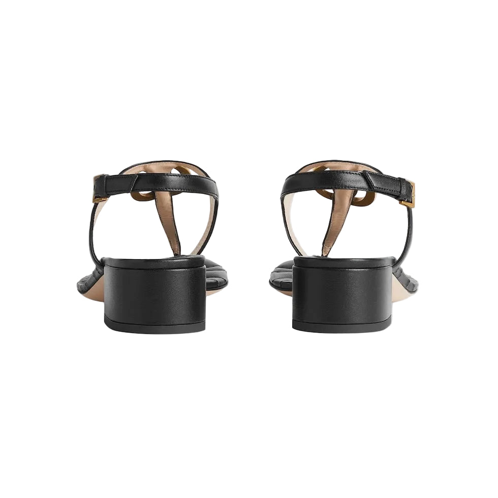Black high-heeled sandals with thin straps on a light gray background