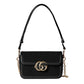 Black handbag with gold chain and logo on a light gray background