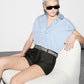 Person wearing a light blue shirt and black shorts sitting on a white chair.