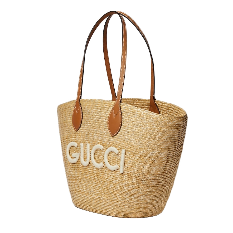 Woven handbag with brown leather straps and 'GUCCI' logo on a light gray background