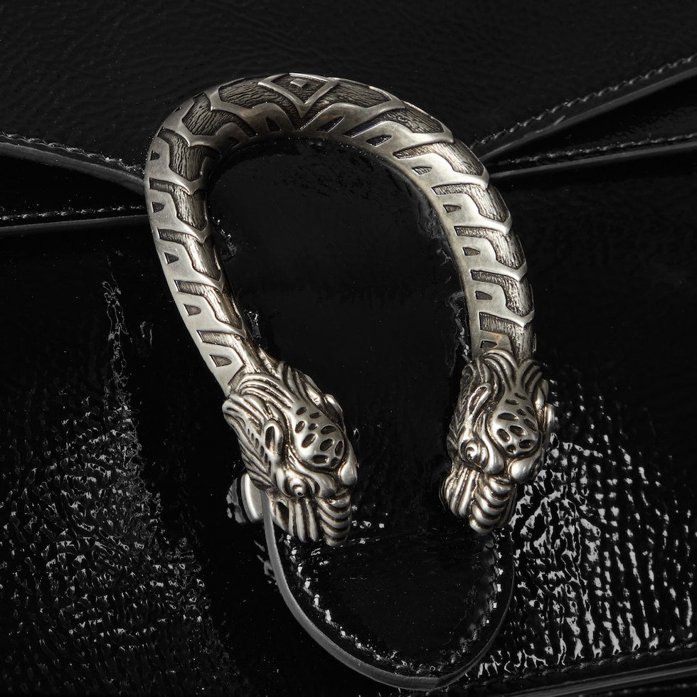 Decorative metal handle with intricate design on a black textured surface