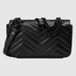 Black quilted handbag with chain detail on a light gray background