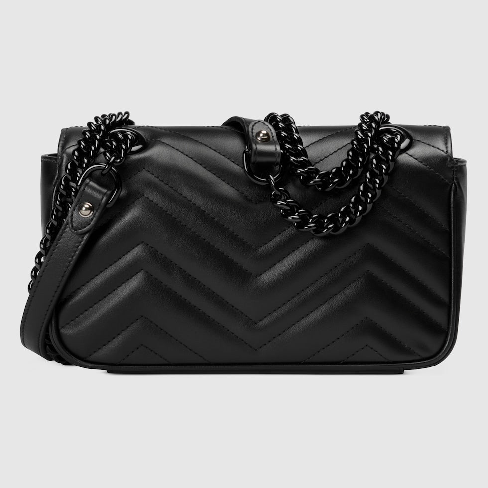 Black quilted handbag with chain detail on a light gray background